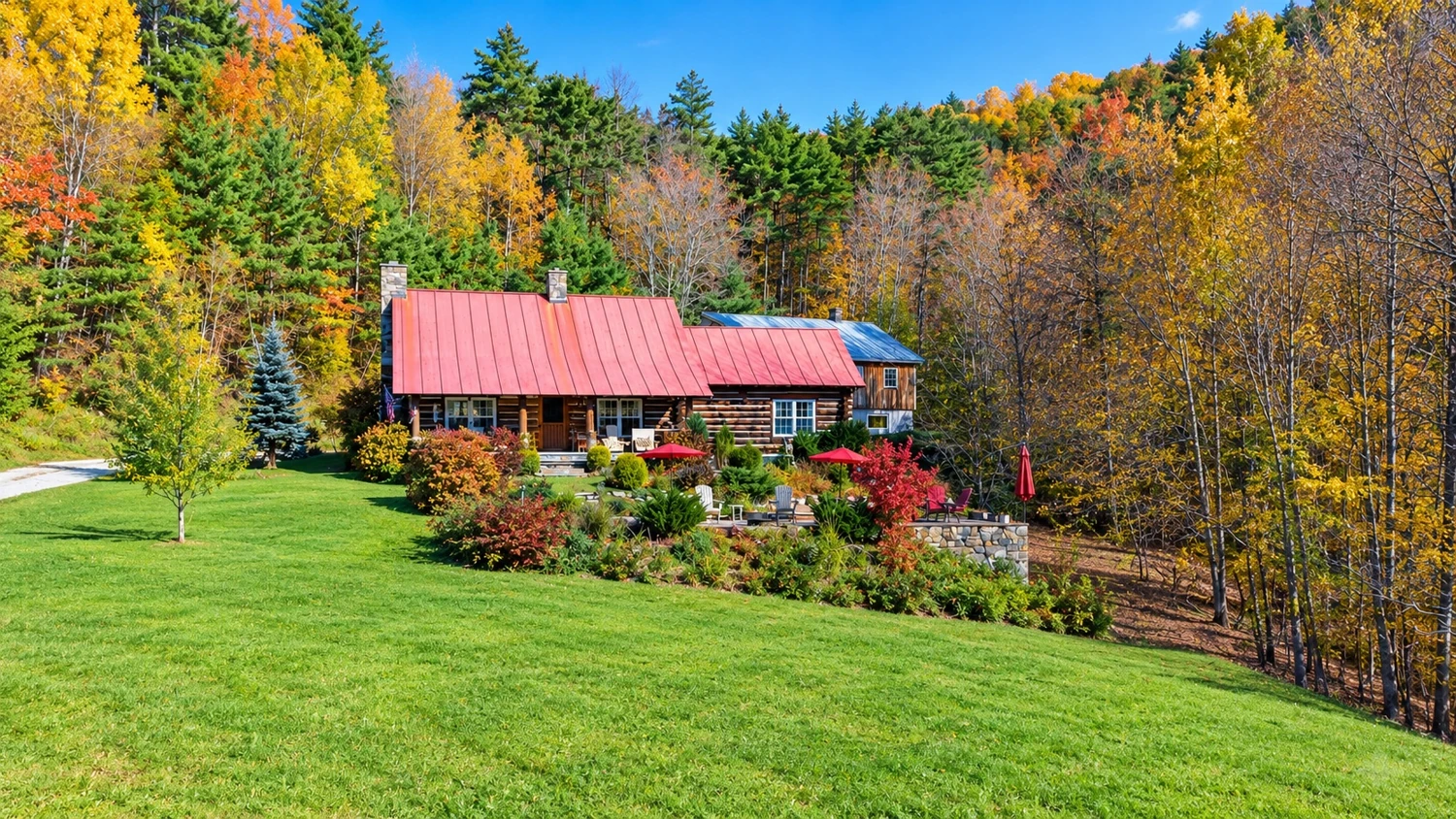 The log home and broad green lawn framed by orange and yellow autumn trees.